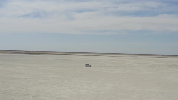 4x4 Car Driving On Vast Makgadikgadi Salt Pan At Daytime Near Kubu Island In Botswana, South Africa. alt