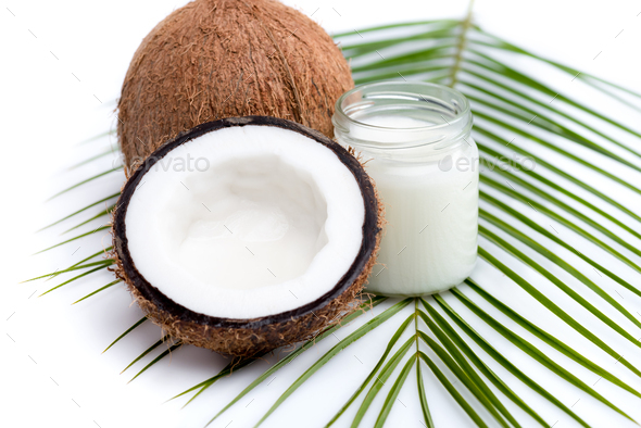 ripe coconuts and organic coconut oil in glass jar on coconut leaf ...