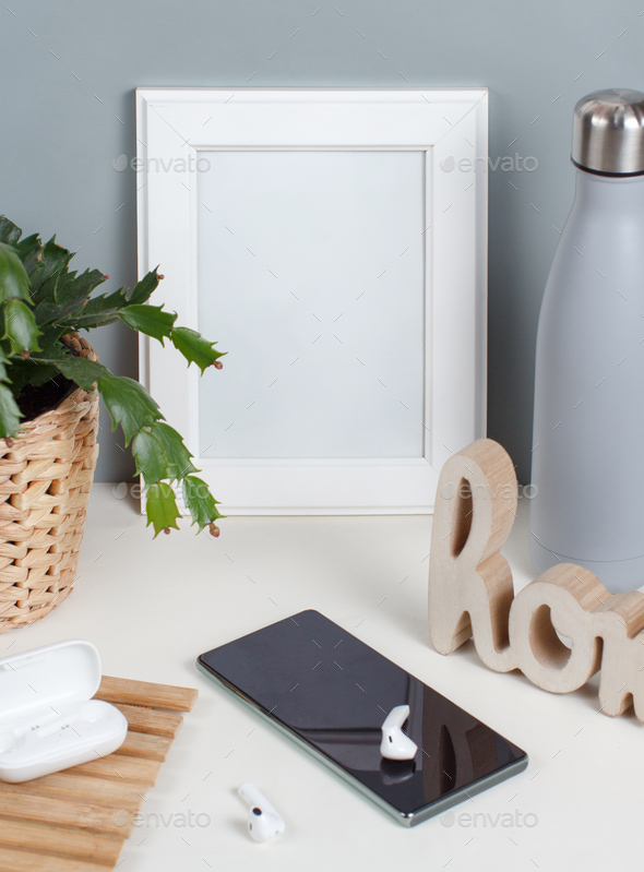 Download Front View Of White Poster Frame Mockup With Modern Gadgets Insulated Bottle And Plant Stock Photo By Katrinshine