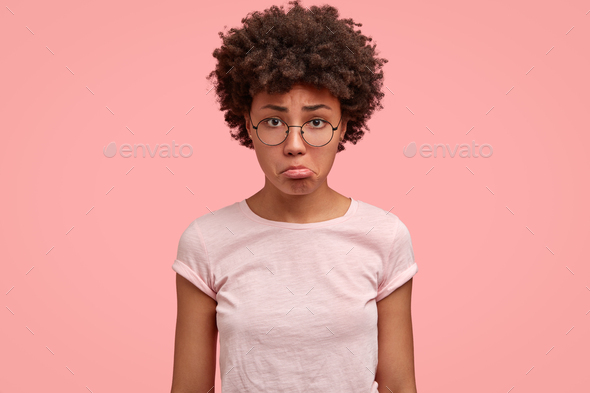 Photo of displeased sad young woman purses lower lip, going to cry as being offended by someone, fee