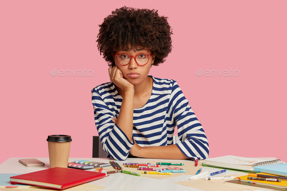Sad woman painter with Afro haircut, has frustrated look at camera, doesnt have insipration for crea