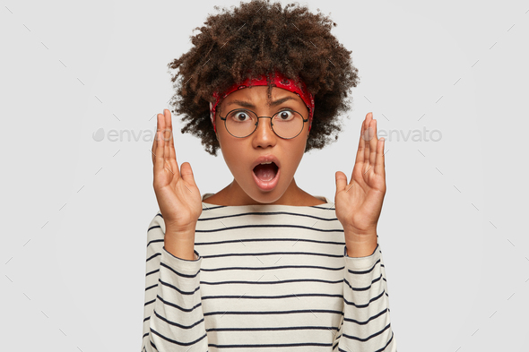 Image of irritated young woman with Afro hairstyle, looks angrily at ...