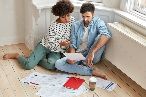 Indoor shot of mixed race family couple analyze data, develop new startup project, study loan agreem