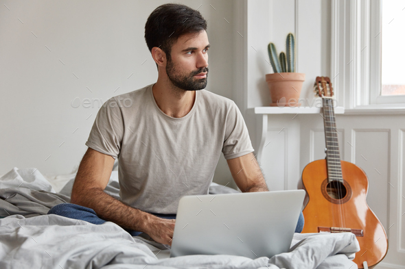 Photo of bearded guy addicted to online communication and apps, starts day with checking email box a