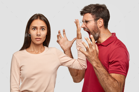 Shut up! Puzzled beautiful woman keeps palm near husbands mouth, asks him stop shouting at her. Jeal