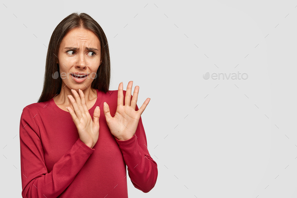 Puzzled anxious woman rejects something unpleasant, keeps palms in no gesture, asks not suggest it a