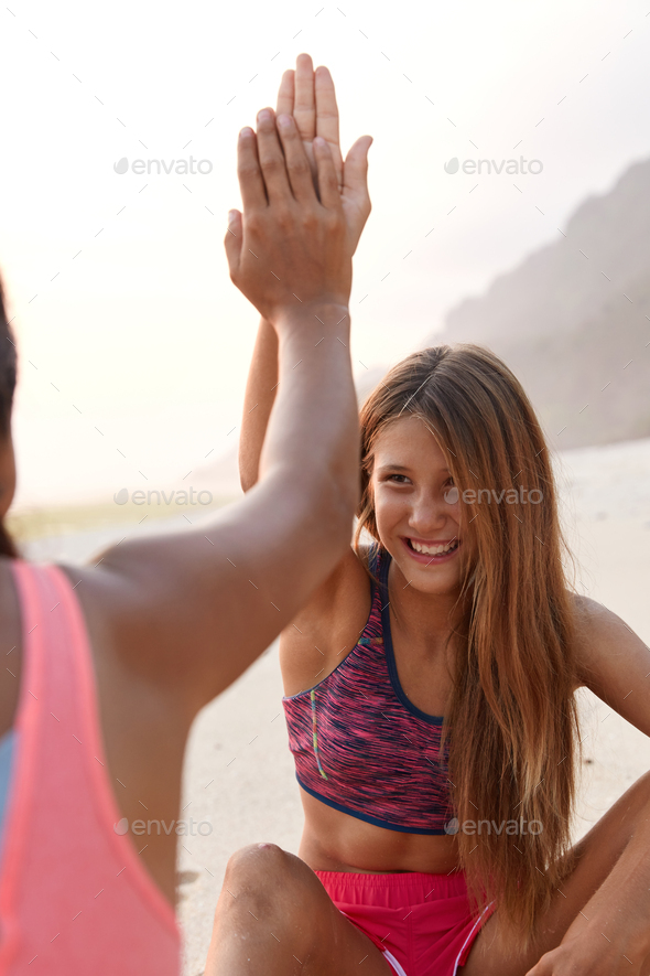 Mixed race women give each other high five, being in nice mood, demonstrate their agreement to have