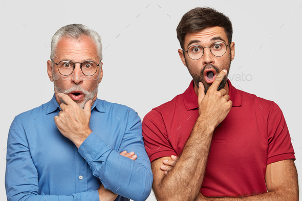 Emotive elderly father and son have shocked faces, hold chins, drop chins with surprisement, recieve