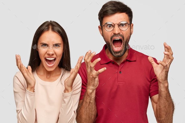 Frustrated annoyed young colleagues, scream angrily, gestures actively, pose against white backgroun