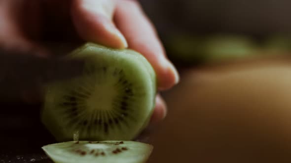 Slicing a Juicy Green Kiwi on a Black Marble Cutting Board alt