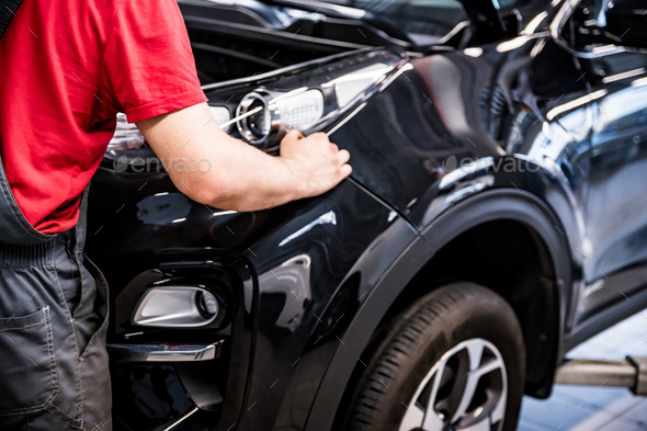 Male car mechanic at autosalon hands on black car business class at autoservice - Stock Photo - Images