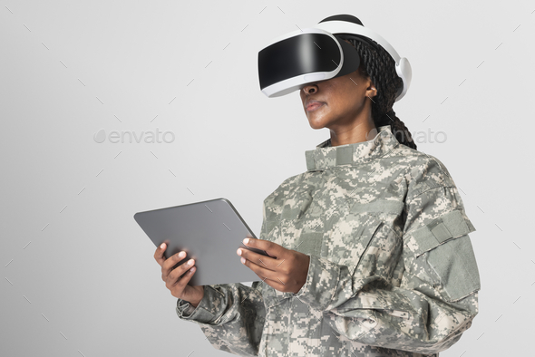 Female soldier wearing virtual reality headset holding tablet