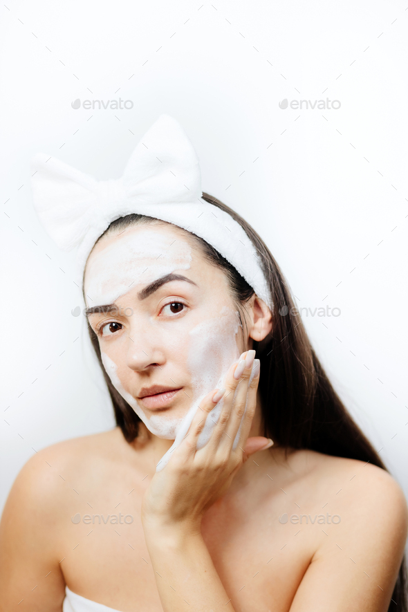Woman applying facial foam on her face