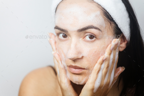 young woman washing face with foam