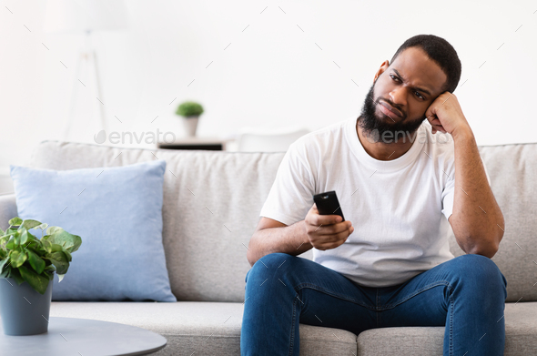 Bored African American Guy Watching Boring Television Program At Home