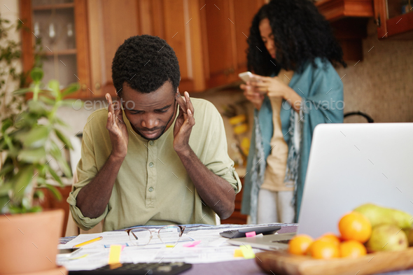 Young African man plugging his ears, feeling stressed, can\'t stand financial stress anymore, not abl