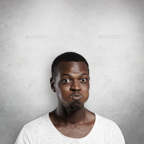 Body language concept. Young dark-skinned man puffing cheeks, trying hard to hold his breath, nearly