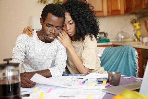 Stressed unhappy young African married couple reading notification from bank, managing family financ