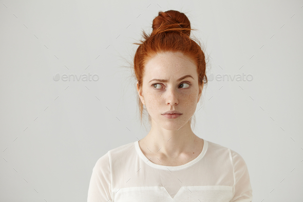 Hmm. Let me think. Studio shot of cute redhead girl with hair knot and freckles looking sideways wit
