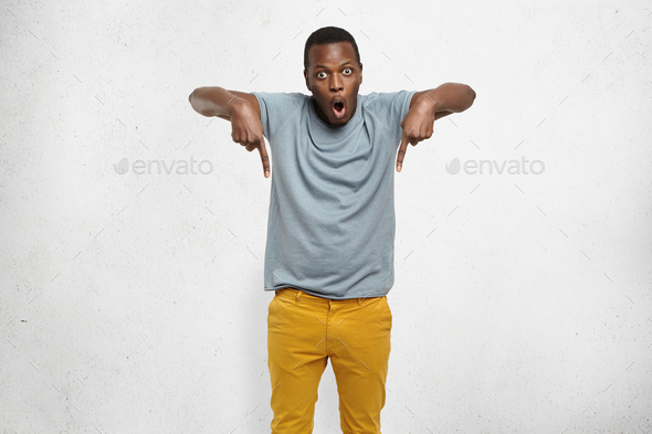 Check this out! Cropped studio shot of attractive excited young African male in t-shirt and mustard