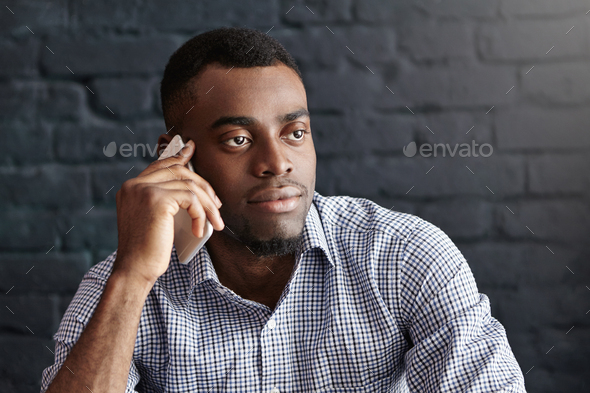Headshot of attractive young dark-skinned male in formal wear having  serious and confident look whil Stock Photo by wayhomestudioo