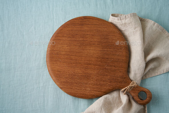 Food background mockup with round wooden cutting board on blue linen textile tablecloth. Placeit - Stock Photo - Images