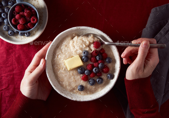 Woman hands with bowl of oatmeal porridge with blueberry, bilberry. Breakfast with fresh berries - Stock Photo - Images