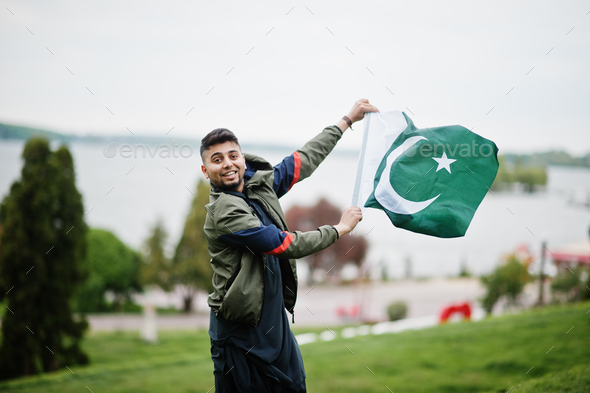 Сonfident pakistani indian muslim arabic boy in grey kameez shalwar suit with Pakistan flag.
