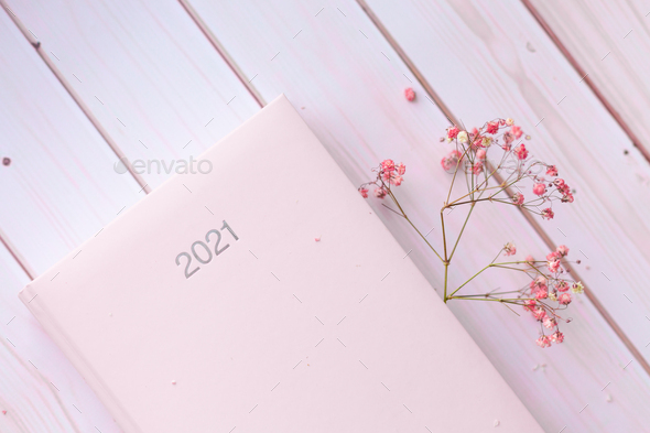 Diary pink organizer with cute pink dried flowers sign 2021 on white pink  wooden background. Stock Photo by kroshka__nastya