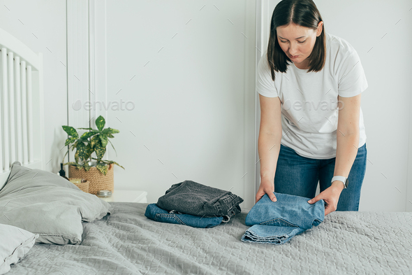Woman folding clothes jeans. Wardrobe analysis, spring update, decluttering concept. Lifestyle