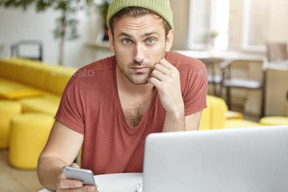 Fashionable man being always in touch, recieves messages from friends, types answer, sits in front o