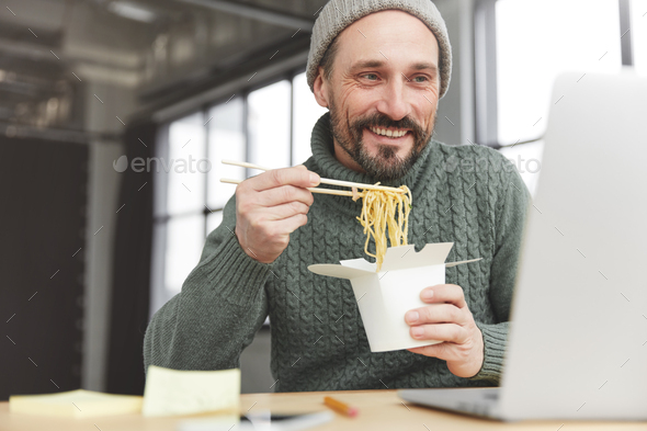 People, fast food, job concept. Middle aged bearded fashionable man has dinner break, eats chinese f
