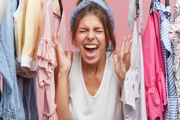 Beautiful woman screaming with negativeness, frowning her face being crazy because of clothes which
