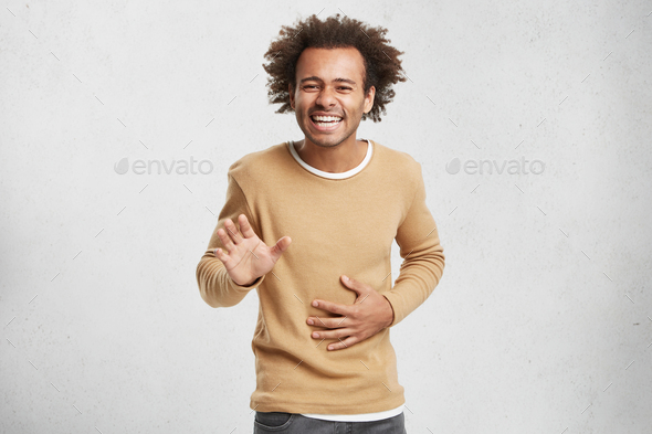 Please, stop it. Overjoyed funny dark skinned male asks friend stop makes laugh, keeps hand on stoma