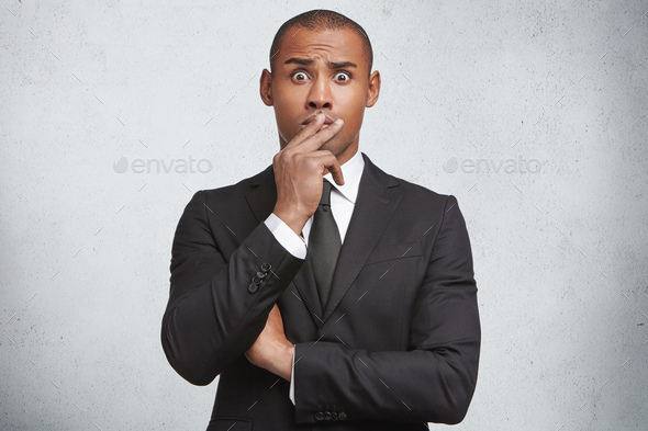 Stunned shocked young male boss or office director covers mouth with hand, surprised to hear about f