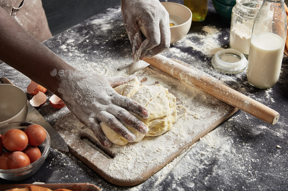Cropped image of talented male cook shows how to bake delicious rolls, prepares dough, kneads it pro