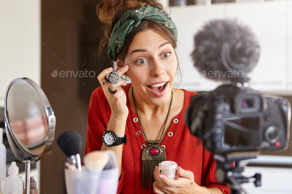 Young female using cosmetic product for her blog, recording tutorial video. Pretty fashionable femal