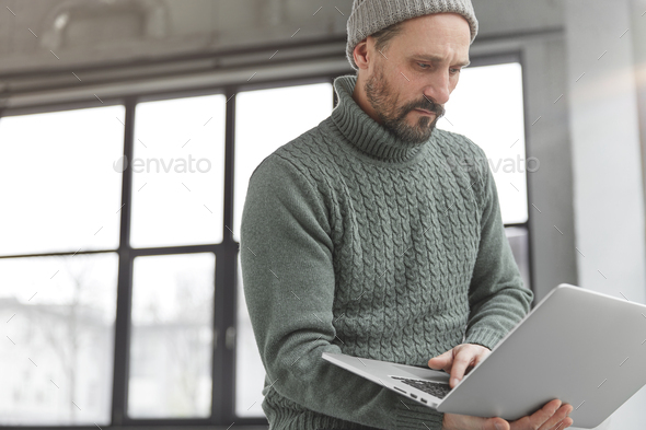 Concentrated middle aged experienced male journalist reads latest news on web pages, searches inform