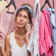 Nothing to wear concept. Beautiful young woman dressed casually feeling  frustrated standing among mu Stock Photo by wayhomestudioo