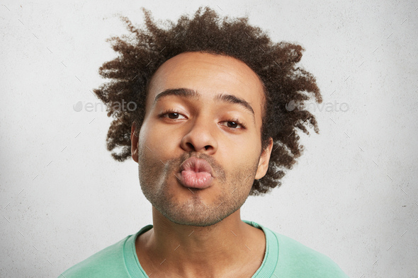 Fuuny Dark Skinned Male With Curly Hair Keeps Lips Rounded Going To Kiss Girlfriend