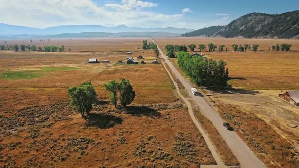 Drone takes off over the road and the endless golden steppe near Mormon Row, Wyoming, USA alt