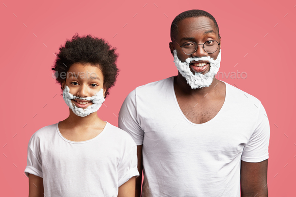 Small mixed race kid imitates father, has foam or shaving gel on face, going to learn shave, have po