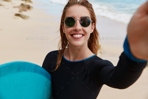 Horizontal shot of wet sexy female model in bathing suit being satisfied  after swimming and surfing Stock Photo by wayhomestudioo