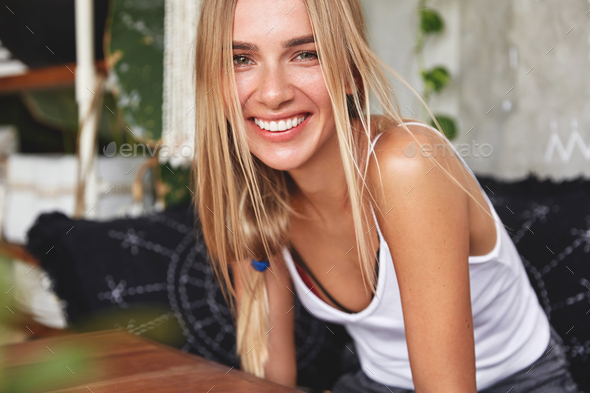 Glad lovely blonde woman has broad cheerful smile, happy to meet with friend or have date with boyfr