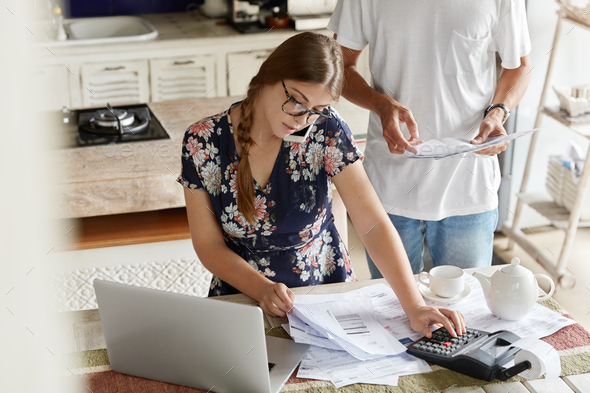 Photo of busy female makes calculations, pays utility bills, works at ...