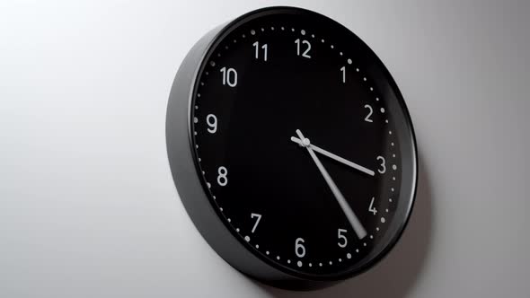 Black Clock Face In Time Lapse On White Wall