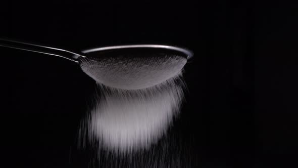 Chef Sifting Flour Through A Sieve To Make Delicious Dessert On Black Background