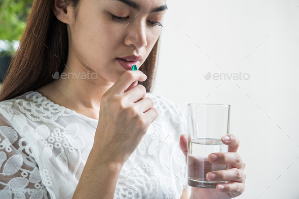 Young woman taking medicine pill after doctor order
