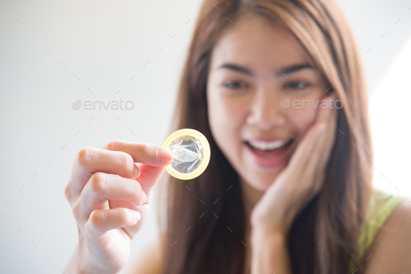 Young woman holding condom prevent pregnancy