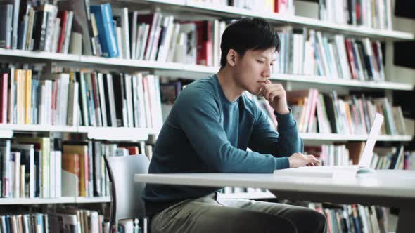 asian adult male student reading in library